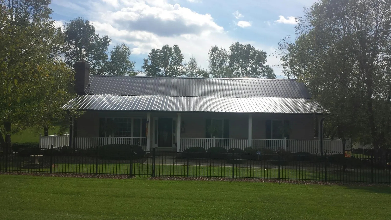 Gray metal roof on a brick ranch with a full width front porch — Gutter Guard Installation work by our crew in Roberts