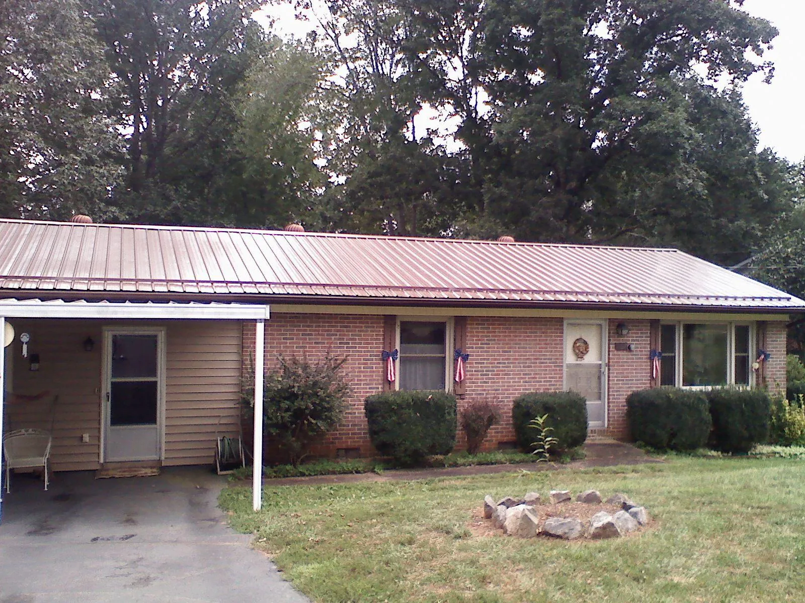 Bronze metal roof and carport on a brick ranch home — Roof Repair work by our crew in Roberts